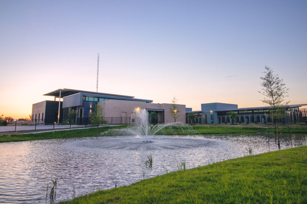 Wide twilight exterior of Lafayette Animal Shelter with retention pond and full campus view