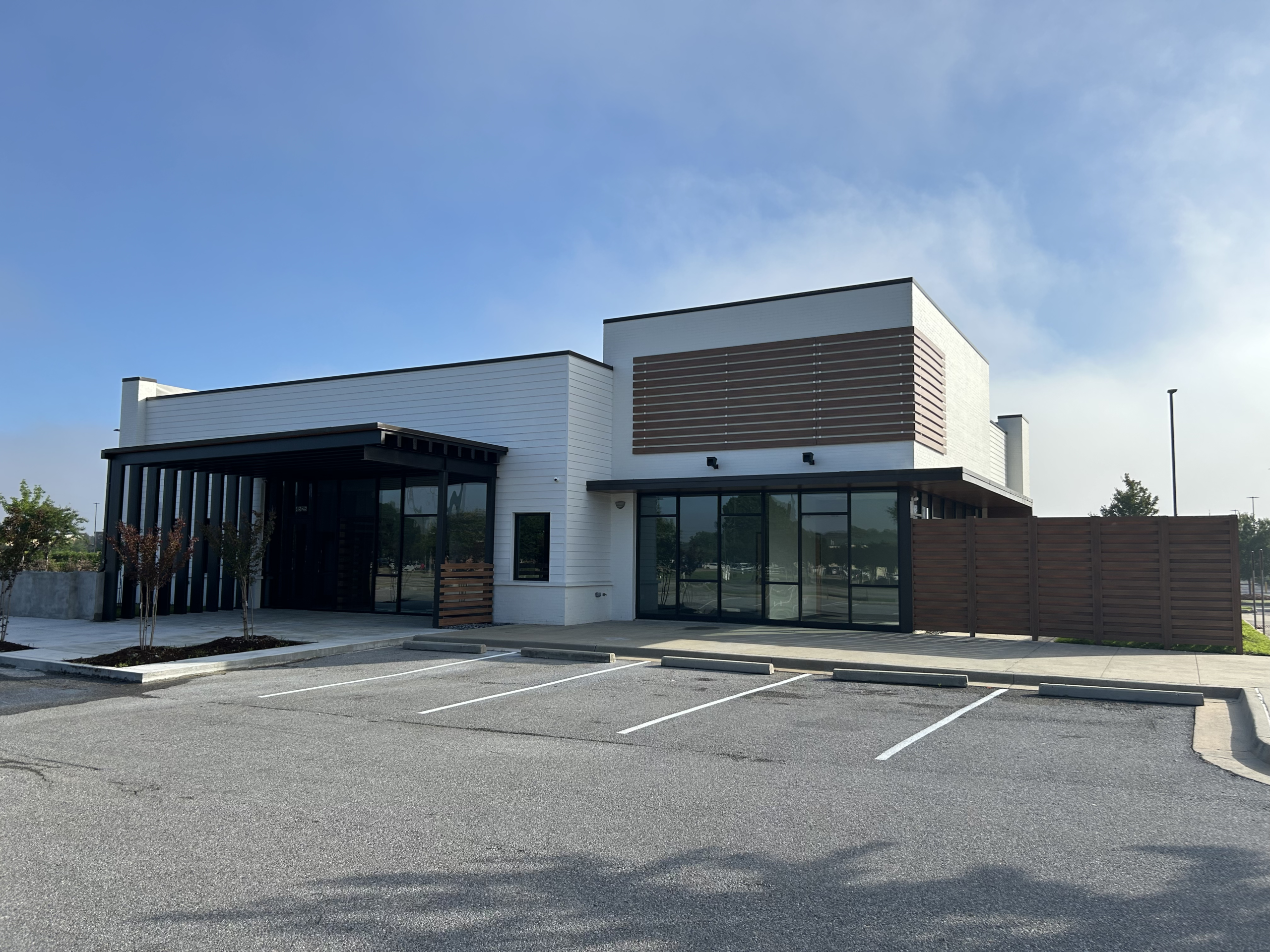 Daytime exterior photograph of the finished CLB The Community Bank branch in Lafayette, modern white and wood facade with parking and entrance
